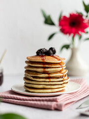 A stack of pancakes with jam from cones on a light background
