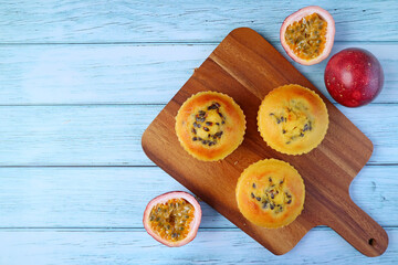 Top View of Homemade Passion Fruit Muffins on Breadboard with Fresh Fruits Scattered Isolated on Wooden Background