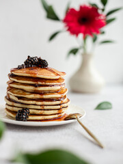 A stack of pancakes with jam from cones on a light background