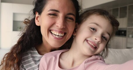 Close up faces laughing young mom little daughter hugging holding device smile look at camera, webcam view. Vloggers record new video vlog, videoconference event with family. Love, modern tech concept - Powered by Adobe