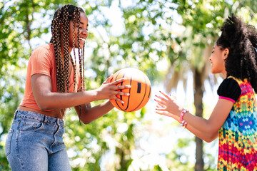 Mother and daughter playing basketball at park.