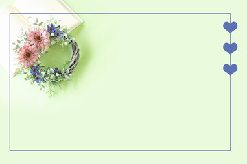 くすみピンクのガーベラと青い花のリースのハートフレーム（緑の背景）