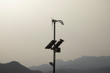 Doves is sitting on a solar and wind panel with the mountains in the back with the bright sun