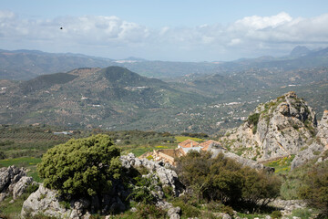 Mountains and trees in a green landscape with some clouds and blue sky