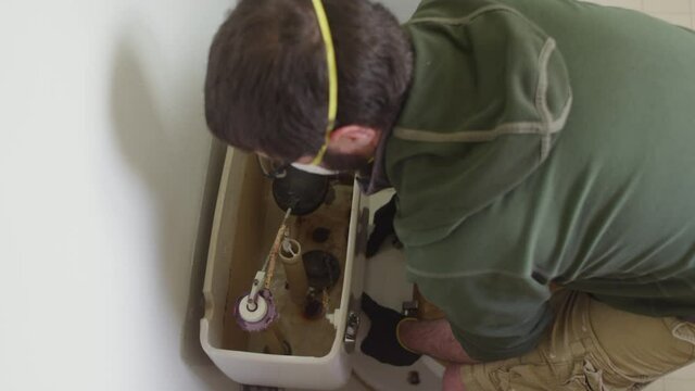 High angle shot of masked man removing toilet during bathroom remodel
