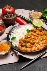 Plate of Traditional Chicken Curry, rice and spices on dark concrete background