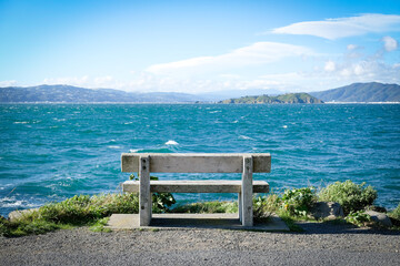Naklejka na ściany i meble Seascope with solitary wooden bench at ocean edge