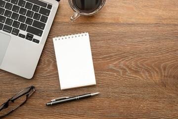 Wood office desk table with blank notebook and office supplies. Top view with copy space, flat lay.