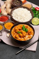 Plate of Traditional Chicken Curry, rice and spices on dark concrete background
