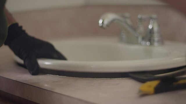 Using a tool to pry out the old sink during a bathroom renovation