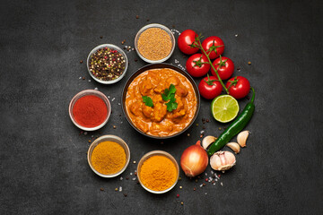 Plate of Traditional Chicken Curry and spices on dark concrete background