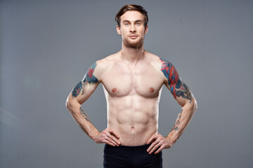 Obraz premium sporty man pumped up press acting out on his arms cropped view gray background