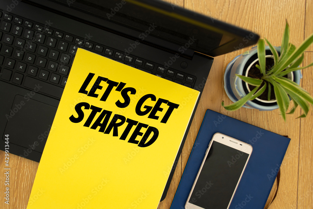 Wall mural notepad on workplace table and written let's get started concept