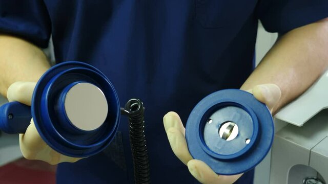 Defibrolator in anesthesia care provider doctor hands Blue medical clothes. First aid. Doctor holding defibrillation electrodes and turninf cap to save children lives. resuscitator at work in clinic