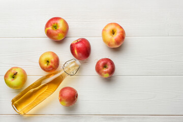 A bottle of apple juice and a few apples on the background of white boards with copy space.