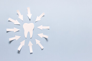 Oral health composition with one paper tooth and and many arrows on blue background