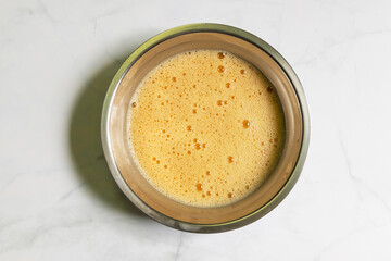 Whipped eggs in a bowl. Top view on white table background.