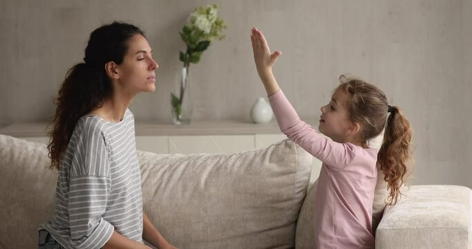 Female speech therapist teaching sound pronunciation to little cute girl. Young mother and her daughter do vocal exercises, learn pronouncing words correctly, voice ability problem correction concept
