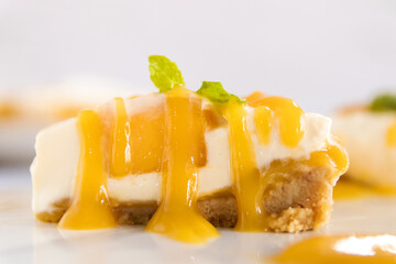 Naklejka na ściany i meble Creamy cheese pie and ripe mango with juicy mango sauce. Sweet and sour dessert sauce.