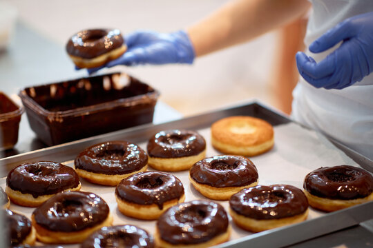 Chocolate topping on donuts in a candy workshop. Pastry, dessert, sweet, making
