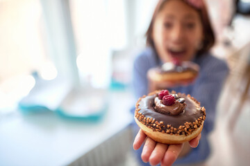 Closeup of a girl holding a chocolate donut of irresistible in her hand and posing in a pastry...