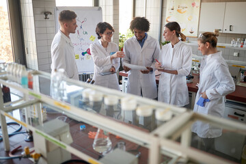 Young chemical students discuss an experiment they will do in the university laboratory. Science,...