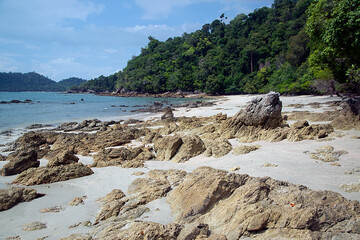 Fototapeta na wymiar Rocky beach with a view of rock and sea. Rocky cliffs and sea waves on sandy beach..