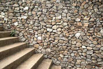 Texture and background wall gray stone with staircase part of the stone wall decorted a building.