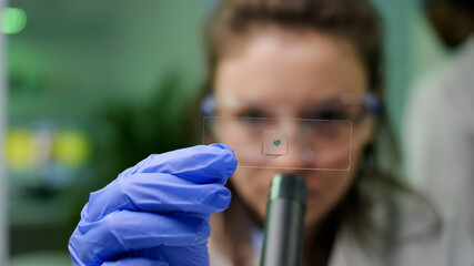 Closeup of chemist scientist looking at green leaf sample checking genetic mutation for biological experiment. Scientist analyzing organic gmo plants while working in microbiology laboratory