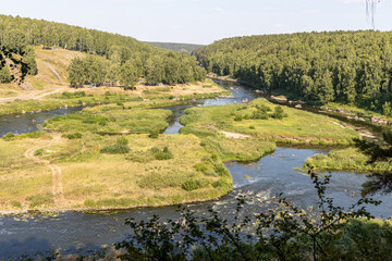 Beautiful river flows among stones and green trees and people with cars in summer day