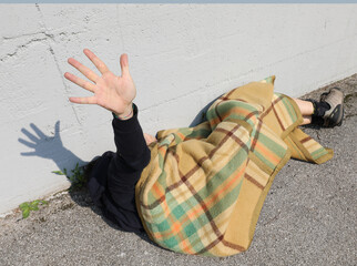 very poor young beggar while he tries to rest on a bed on the sidewalk of the metropolis