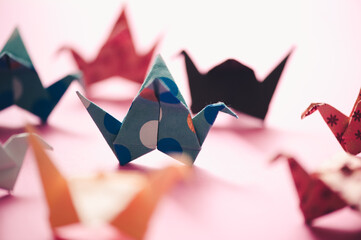 Toy origami group of decor crane from colorful paper close up. Playful.