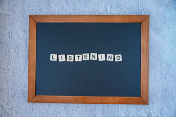 Listening sign of English learning skills written on Blackboard. Chalk board with wooden frame with Listening sign on grey concrete wall background. Horizontal