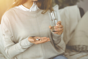 Close-up woman holding pills time to take medications, cure for headache. Medicine concept during self isolation and Coronavirus pandemic