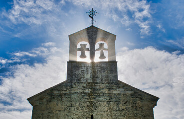 Sol atraves de la espadaña y campanas de la iglesia San Juan evangelista en Arroyo de la...