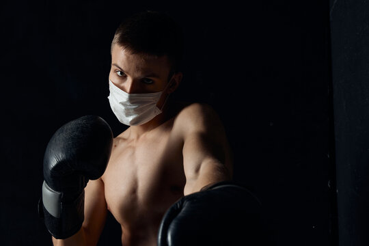 boxer in a medical mask and boxing gloves on a black background