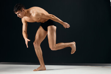 Fototapeta na wymiar male bodybuilder with muscular body in black shorts posing dark background