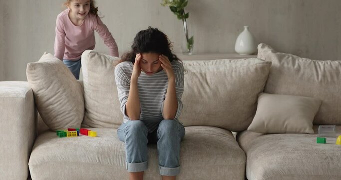 Preschool 5s little daughter makes mom mad by noisy behaviour jumps and screams near her while she seated on sofa. Disobedient and misbehaved kid, upbringing difficulties, disrespect to parent concept