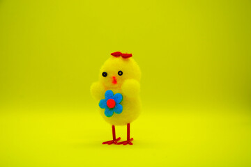 Decorative yellow chicken with a flower on the chest and a bow on the head