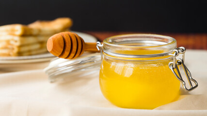 A jar of fresh fragrant honey on the table. Image with selective focus