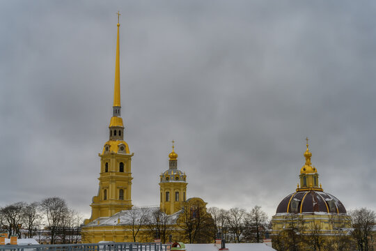 The spire and golden domes of the cathedrals of the Peter and Paul Fortress in St. Petersburg (Russia) on a spring cloudy day. Panoramic view of the historic fortress from above. Patterns, clocks 