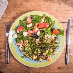 Fried scrambled eggs with asparagus, spinach and tomatoes in a large plate on a rustic wooden table, top view, close-up - simple rustic breakfast