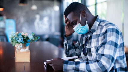 Stress african man wearing face mask in cafe with reading a book © arrowsmith2