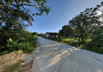 An ultrawide angle shot of old wooden house on the side of the white road in the village