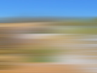 Defocused landsgape with sand, grass and sky. Brown, green, blue strips. Smooth gradient. Speed lines. Multicolored blurry background. Abstract design. Textured surface