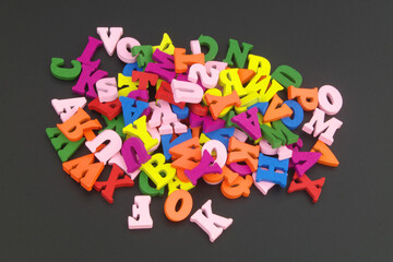 Heap of colorful wooden letters on black table.