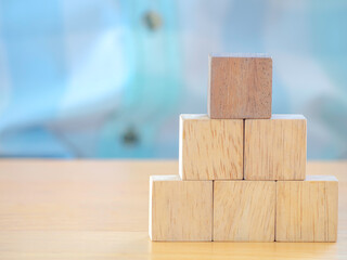 Hand arranging wood cube stacking as stair step shape on wooden table .Business concept create symbol or logo, development, growth and management concept.