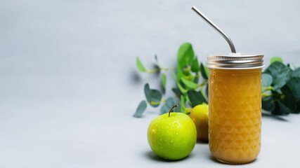 Fresh squeezed apple juice with pulp or fruit smoothie. Apple drink in glass with metal straw on grey background, copy space. Dietary beverage, healthy drink and dieting concept.