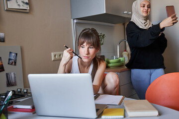 Woman holding pencil and studying attentively while doing her home task