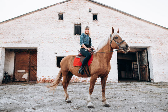 Young woman riding a horse in countryside on rancho